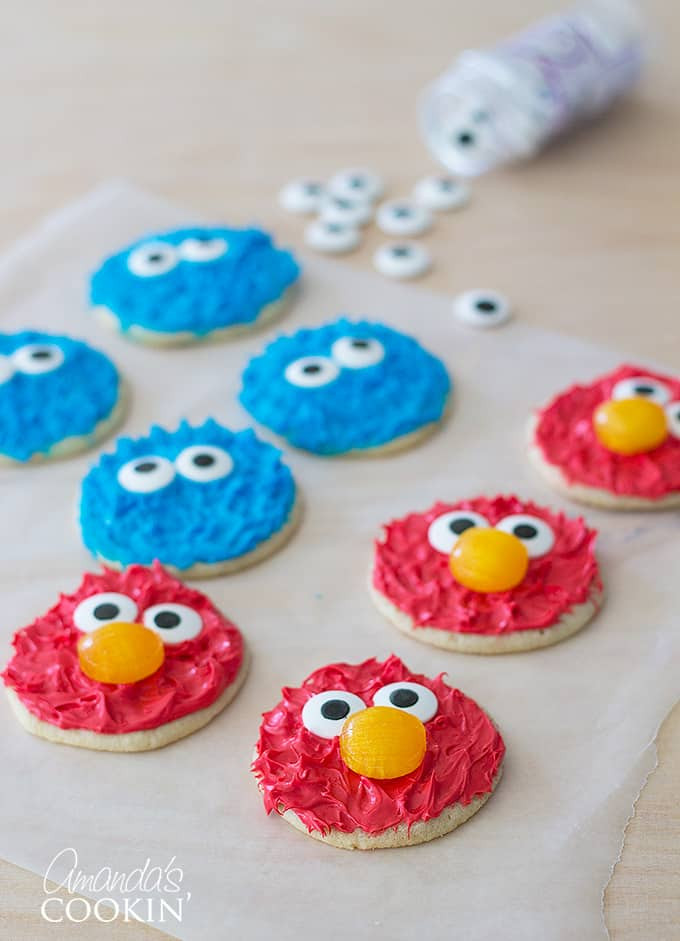 A batch of Elmo and Cookie Monster decorated cookies laid out on parchment paper, ready to be enjoyed.