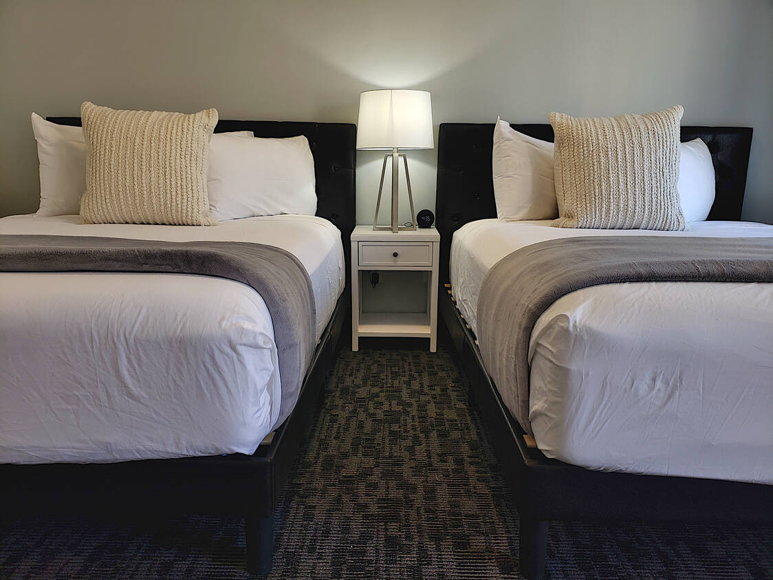 Nightstand and bedside lamp in a King Room at Main Street Motel, offering convenient lighting and storage.
