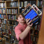 Harrison Lowe, an employee at Dickson Street Bookshop in Fayetteville, organizes reference books, continuing the legacy of this beloved independent bookstore.