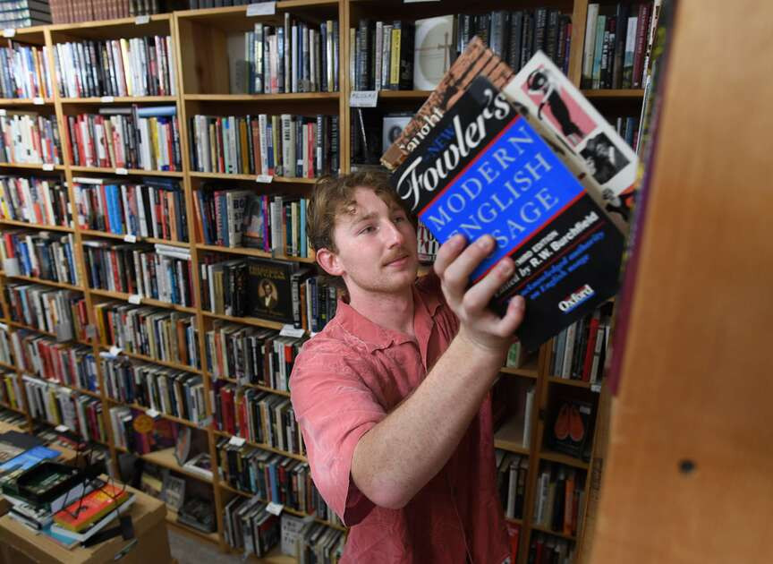 Harrison Lowe, an employee at Dickson Street Bookshop in Fayetteville, organizes reference books, continuing the legacy of this beloved independent bookstore.