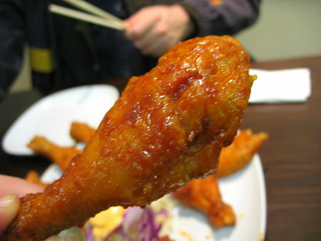 Spicy drummette, a popular Korean fried chicken piece at Bonchon 38th Street NYC, coated in vibrant red chili sauce.