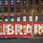 Exterior view of Adams Street Library in Brooklyn showcasing its brick facade and large windows, designed by WORKac.