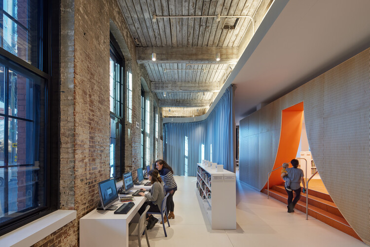 Reading area by the windows at Adams Street Library, providing natural light and views for library patrons.