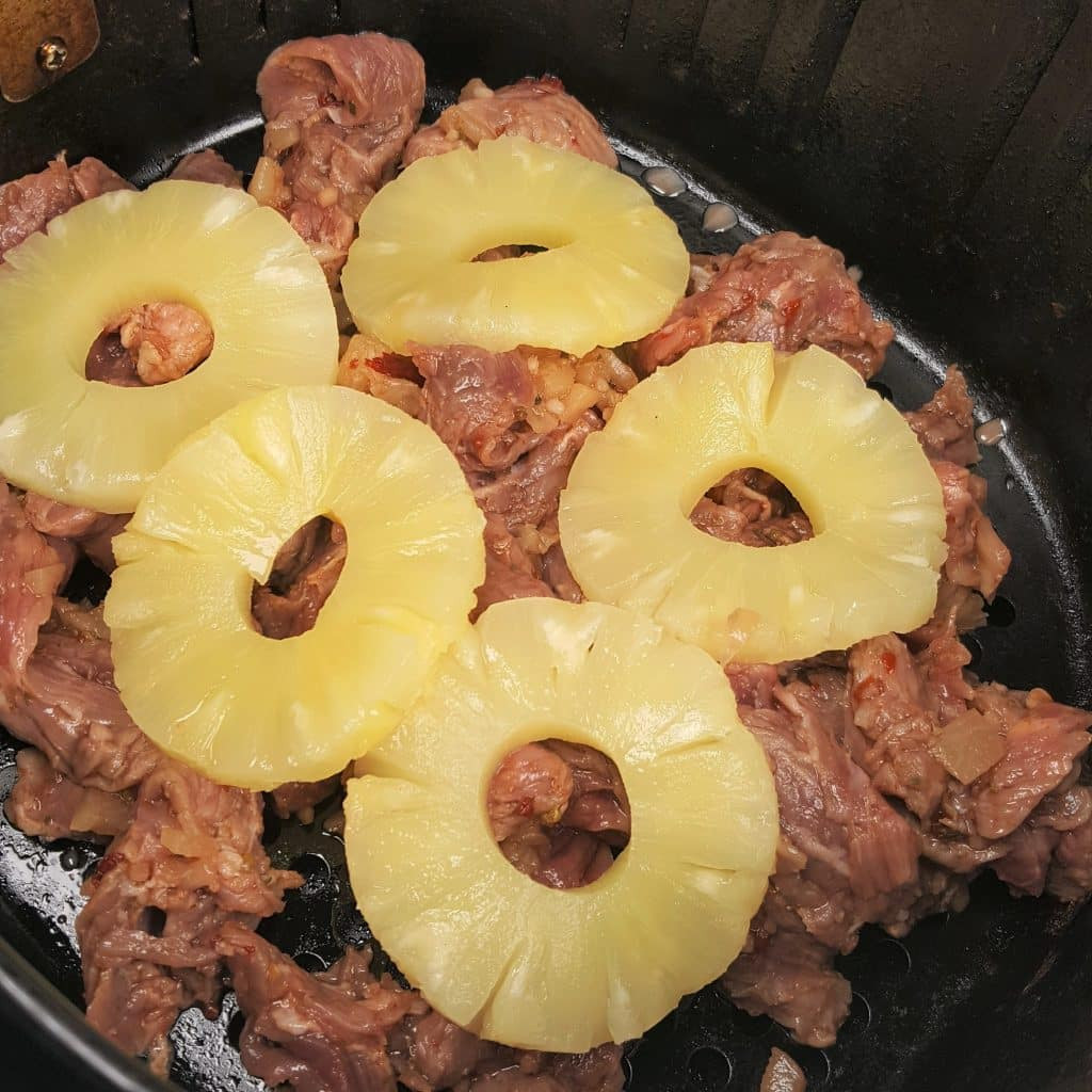 Flap meat marinating with pineapple rings on top for air fryer Tijuana street tacos.
