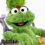 Ameera Sesame Street Muppet character smiling in a purple shirt