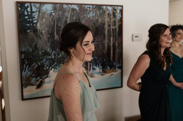 Bridesmaids in stylish green dresses assist the bride with her veil, getting ready for an Anchorage wedding