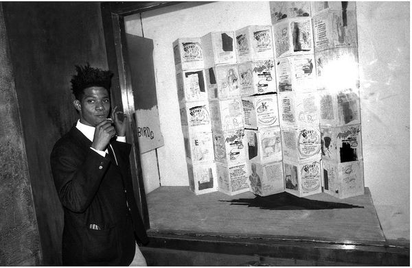 Black and white portrait of Jean-Michel Basquiat in his studio window in 1985