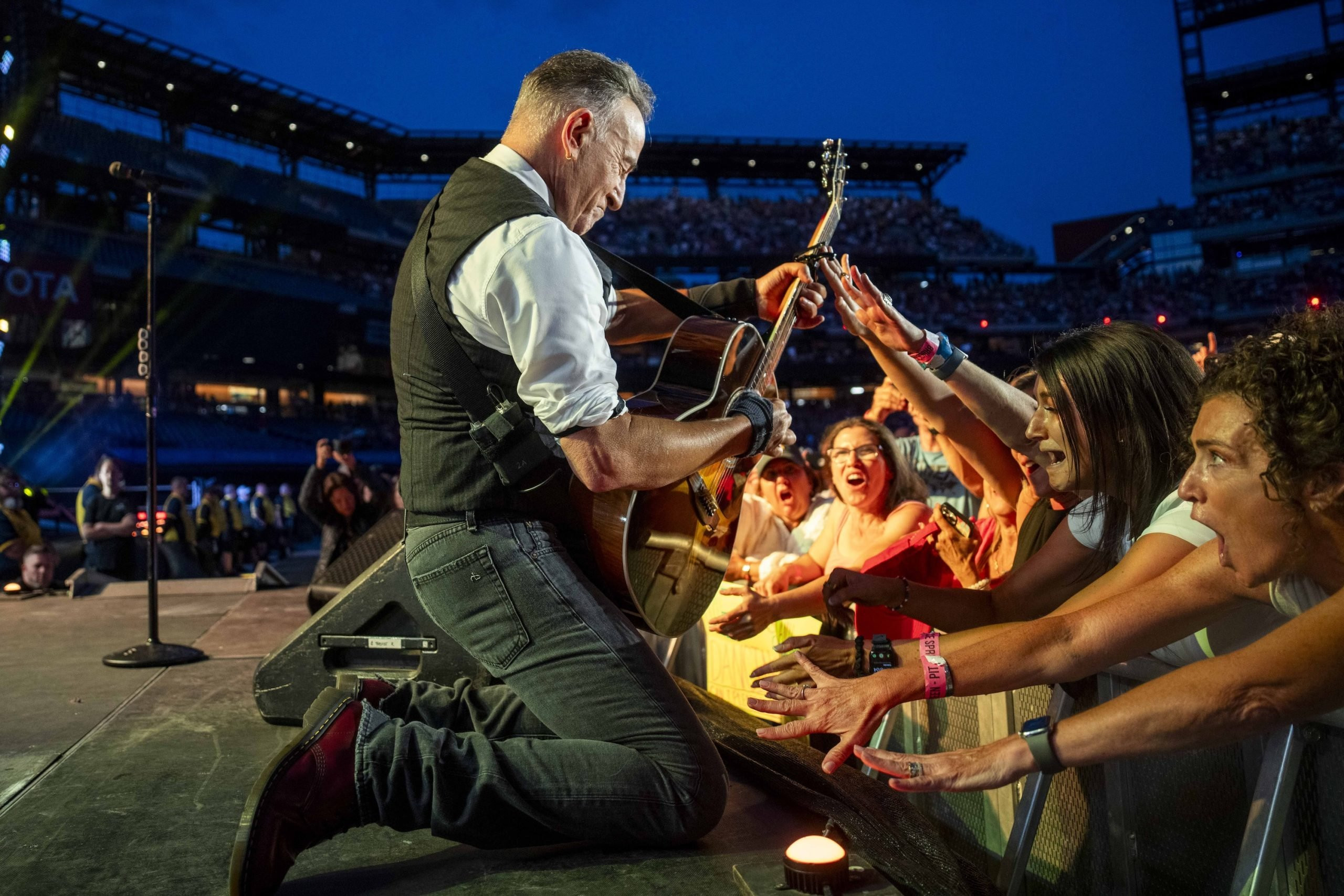 Bruce Springsteen performing intensely under stage lights at Citizens Bank Park in Philadelphia.