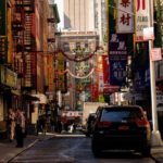 Street vendors and bustling sidewalks on Canal Street in Chinatown, NYC, filled with shoppers and merchandise.