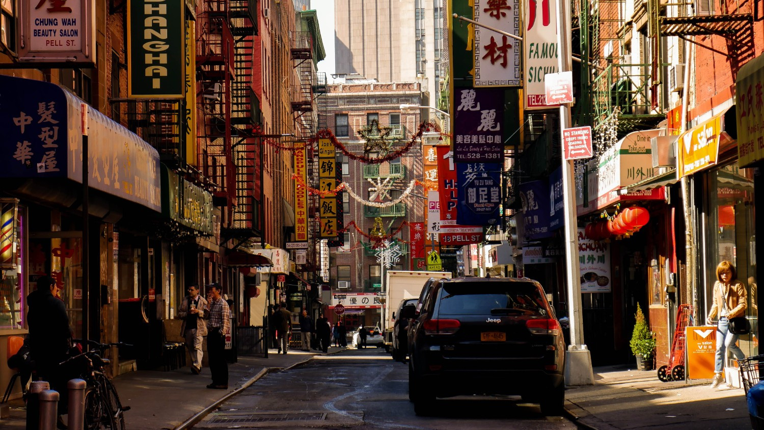 Street vendors and bustling sidewalks on Canal Street in Chinatown, NYC, filled with shoppers and merchandise.