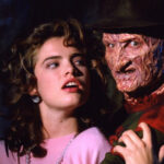 A shadowy figure with bladed fingers emerging from darkness, the iconic imagery of Freddy Krueger in A Nightmare on Elm Street.