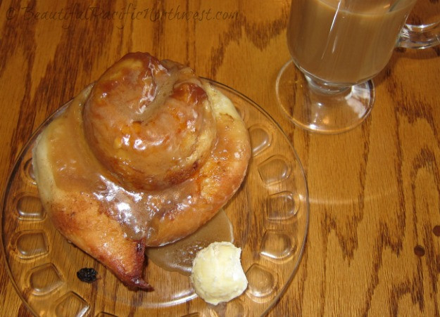 Close-up of a delectable cinnamon roll, a signature baked treat at First Street Haven in Port Angeles, featuring rich icing and buttery layers