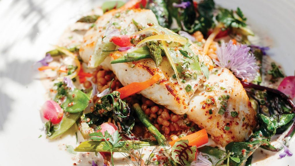 An artful presentation of a fish dish with wheat berries and herbs at Cherry Street Cellar restaurant in Columbia Missouri, highlighting fresh ingredients.