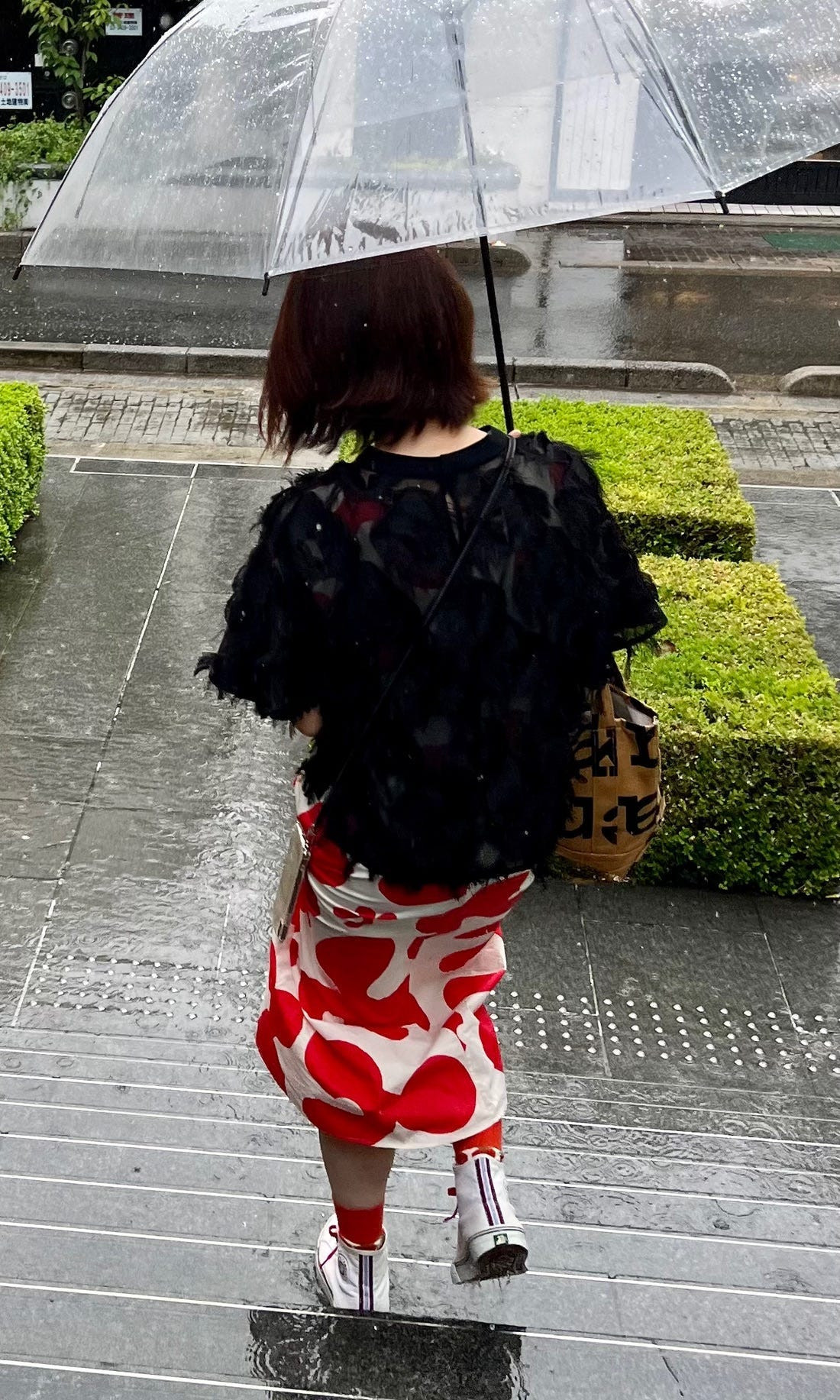 A street style shot capturing layered and voluminous black outfits, reminiscent of Comme des Garçons' deconstructed style.