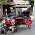 Tuk tuks, a common mode of transport, navigate the bustling streets of Siem Reap, Cambodia, showcasing the vibrant street life.