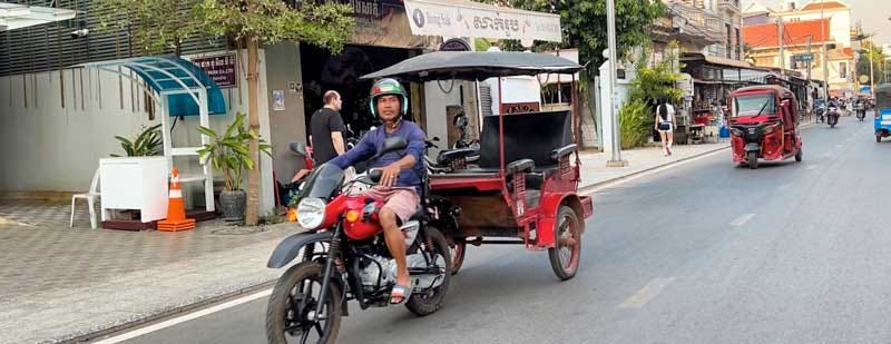 Tuk tuks, a common mode of transport, navigate the bustling streets of Siem Reap, Cambodia, showcasing the vibrant street life.