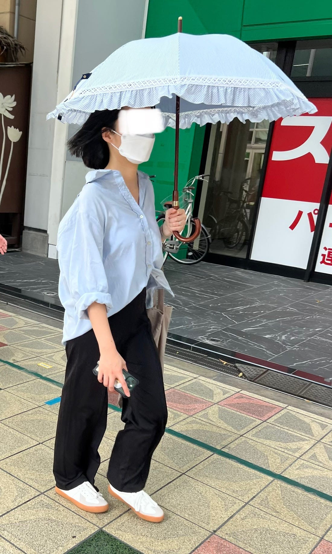 Street fashion image capturing a person in a large, striped shirt and dark pants, highlighting the use of stripes and patterns in Japanese clothing.