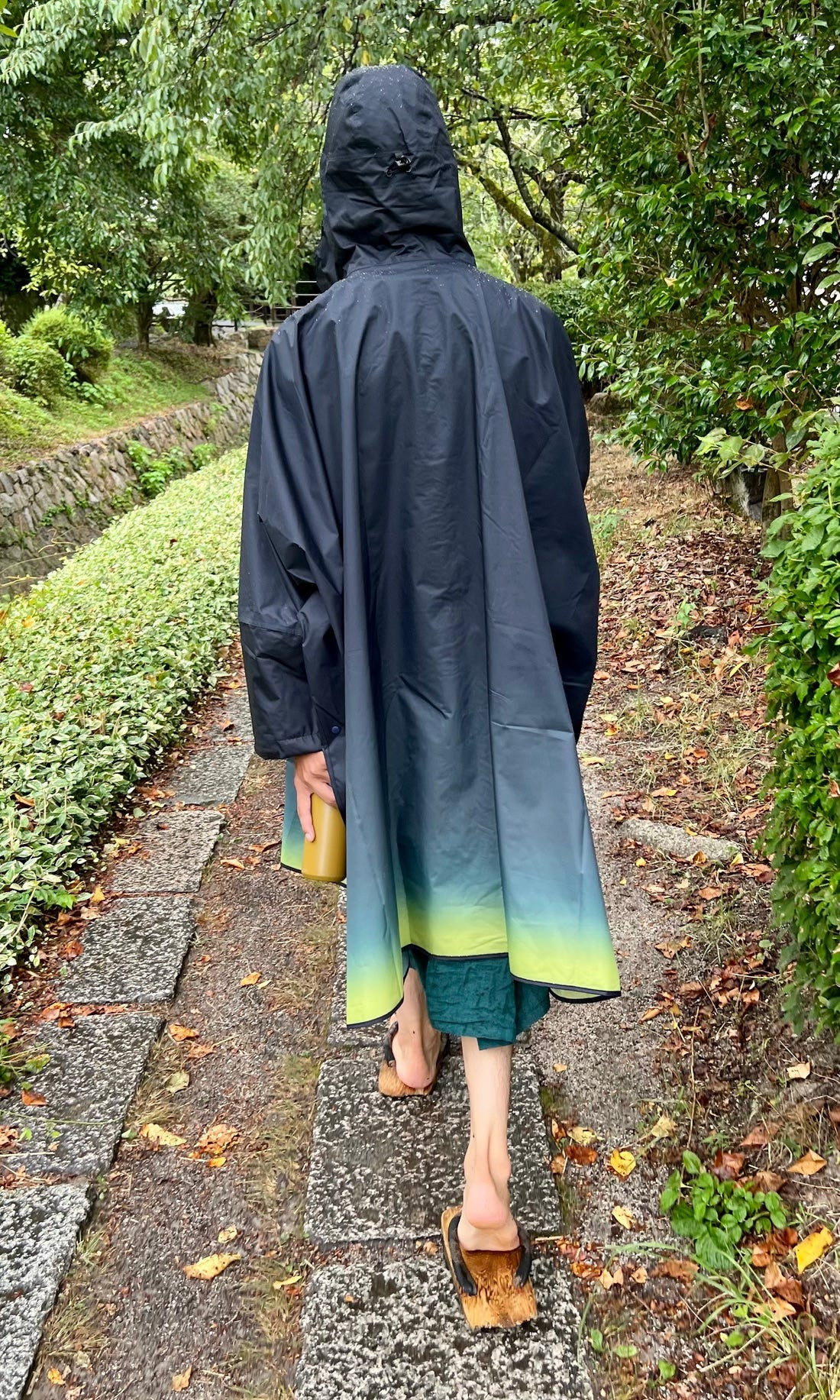 Street style photograph of a man in traditional wooden sandals (geta) with a modern outfit, blending traditional and contemporary styles in Japan.