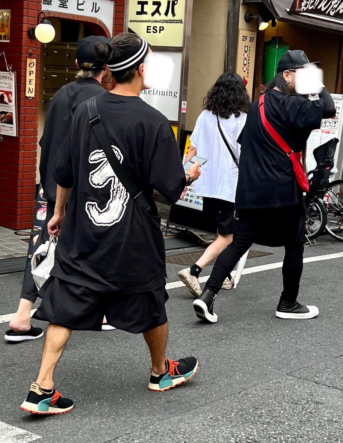 Street style photograph of a couple with coordinated black and white outfits and hats, showcasing a stylish and cohesive osoroi look.