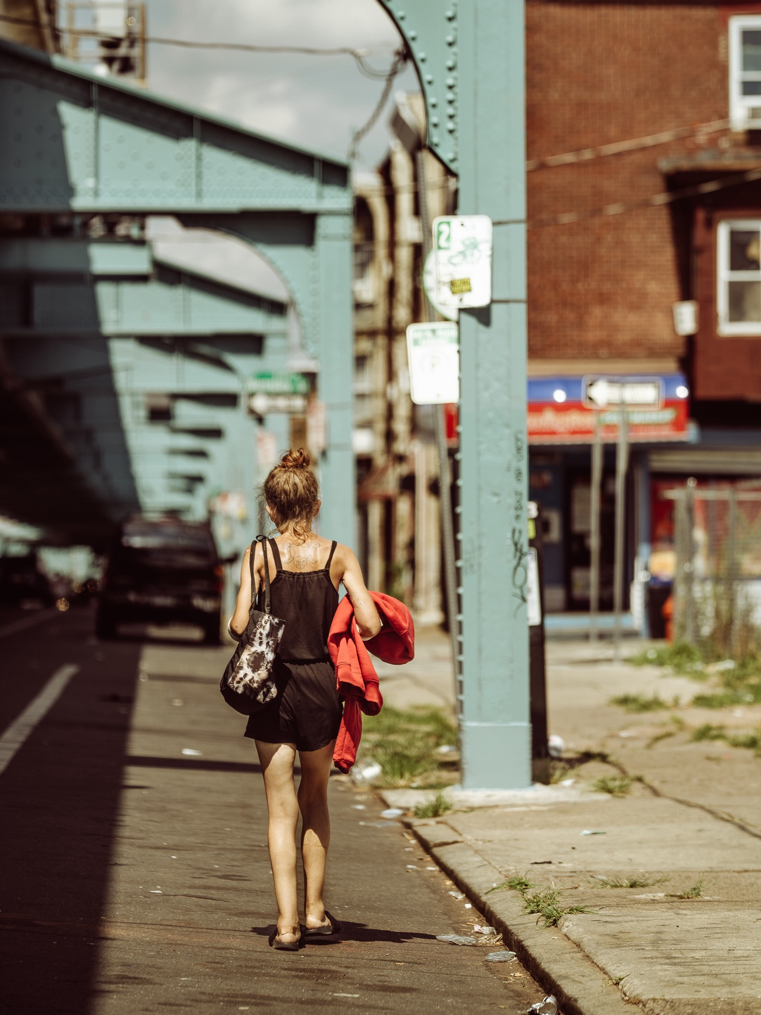 A young woman walking along Kensington Avenue, Philadelphia, representing the vulnerability and challenges faced by women in the area.