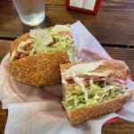 Italian Combo sandwich shown in a plastic tray at a table in Mario