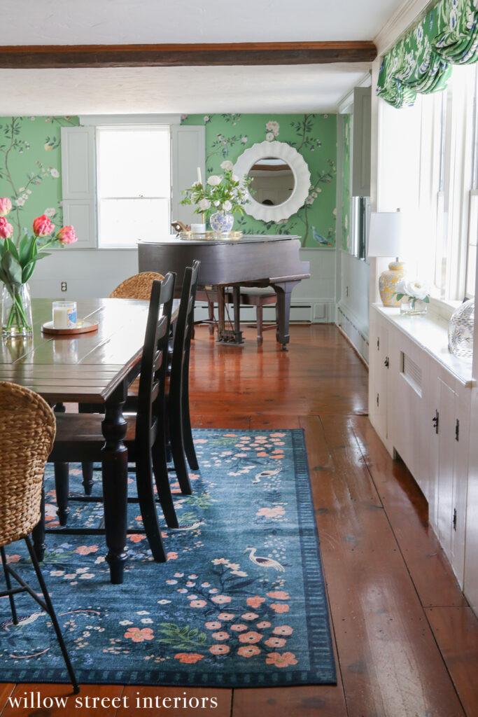 A corner of the living room in a Norfolk home by Willow Street Interiors, featuring a patterned armchair, textured pillows, and a glimpse of the piano, highlighting the eclectic and colorful design palette.