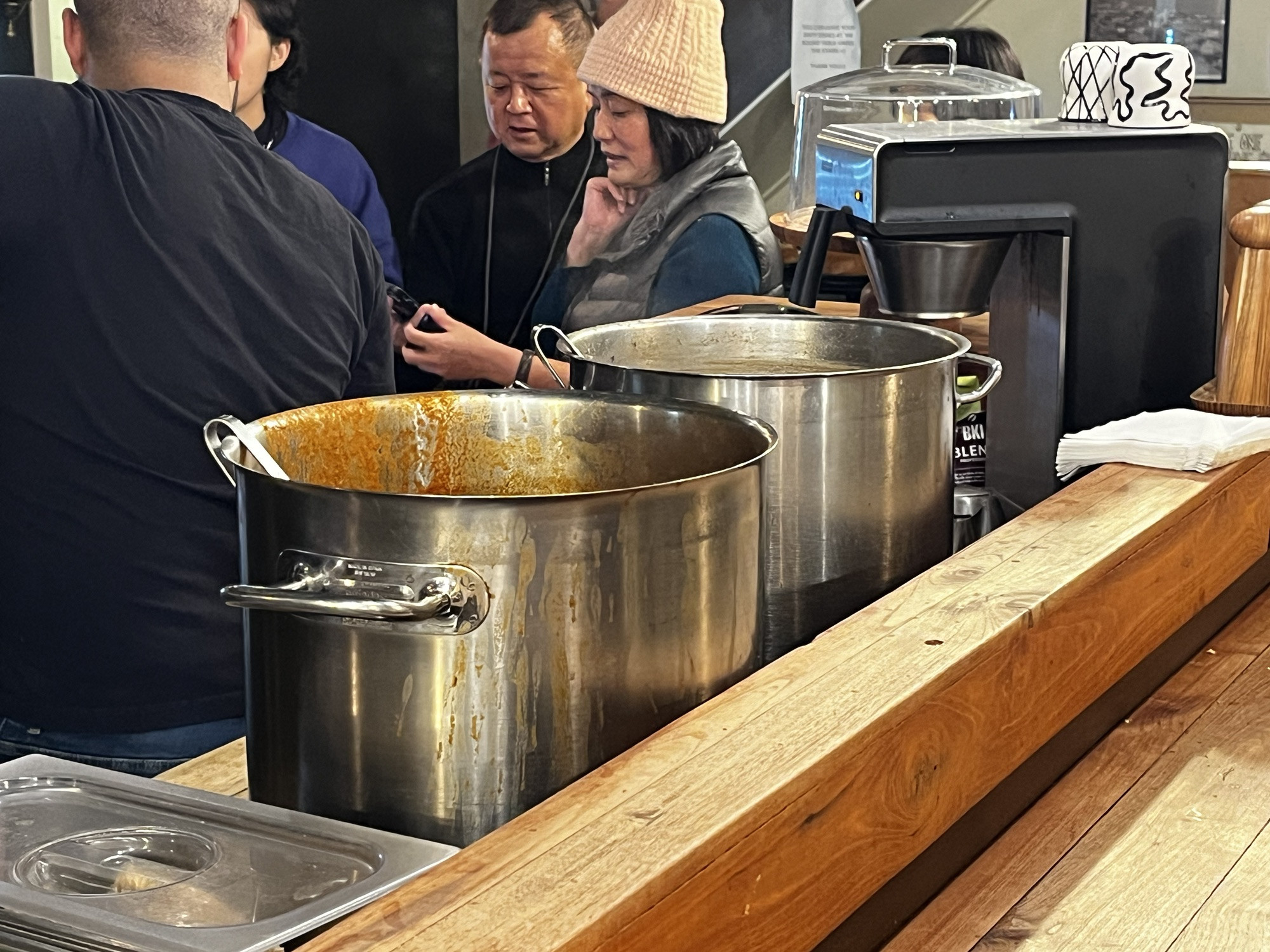 A person holding a glass of Einstok White Ale at Icelandic Street Food in Reykjavik, alongside the soup serving area.