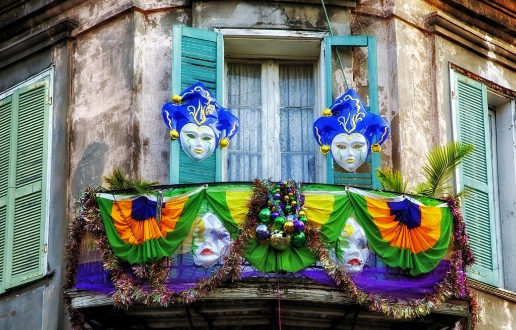 A vibrant street scene in New Orleans' French Quarter during Mardi Gras, showcasing colorful buildings and lively crowds.