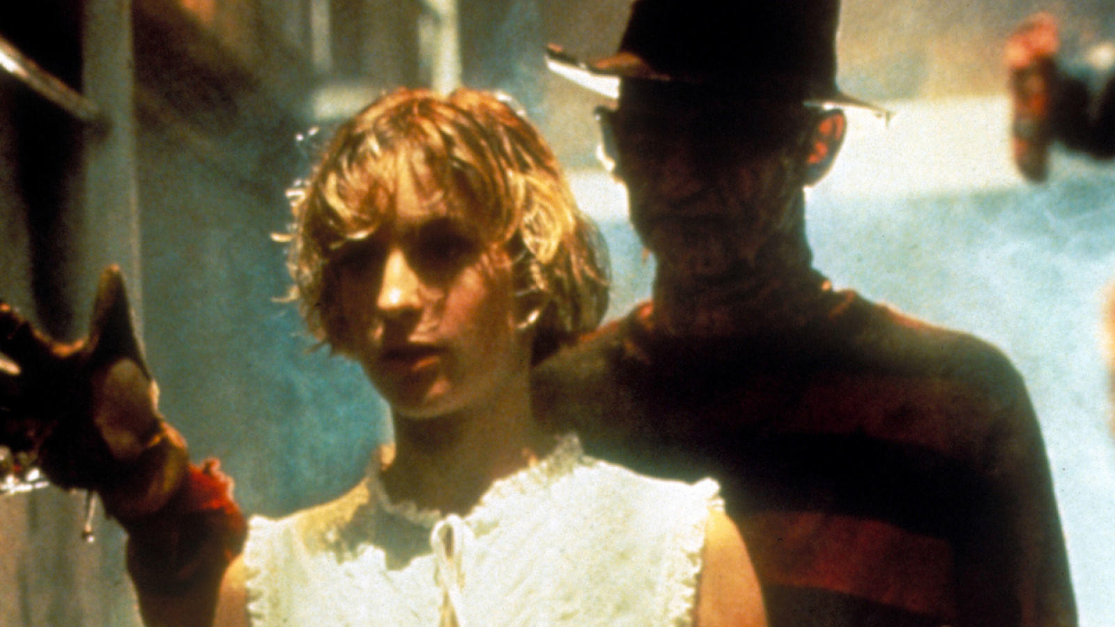 The movie poster for A Nightmare on Elm Street (1984), featuring Nancy Thompson facing Freddy Krueger in a dreamlike, fiery landscape.