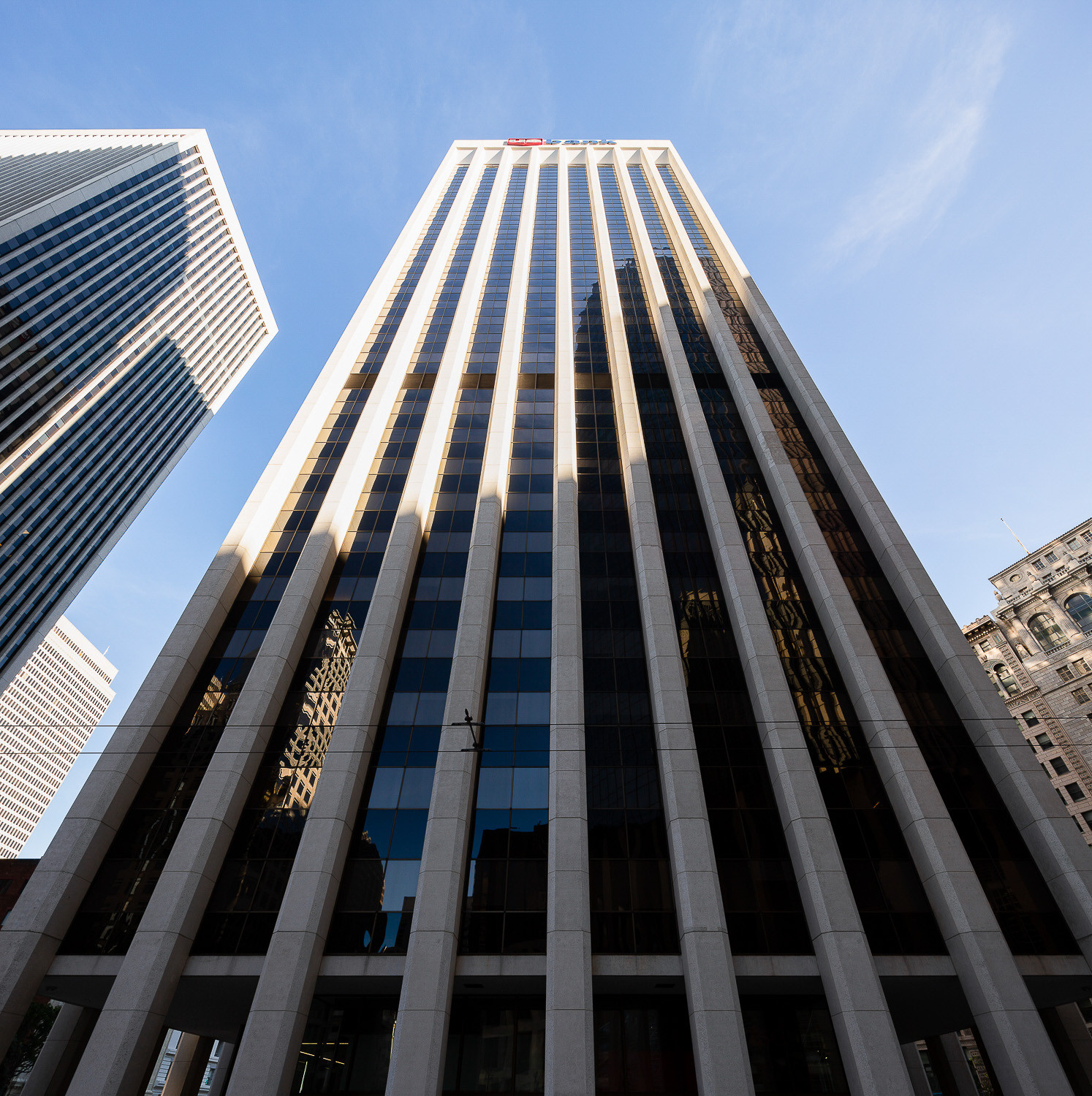 Looking up at One California Street, highlighting its modernist design and concrete pillars in San Francisco's Financial District