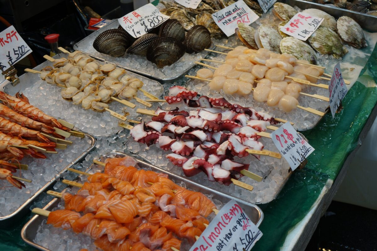 Various food stalls at Kuromon Market in Osaka offering diverse street food.