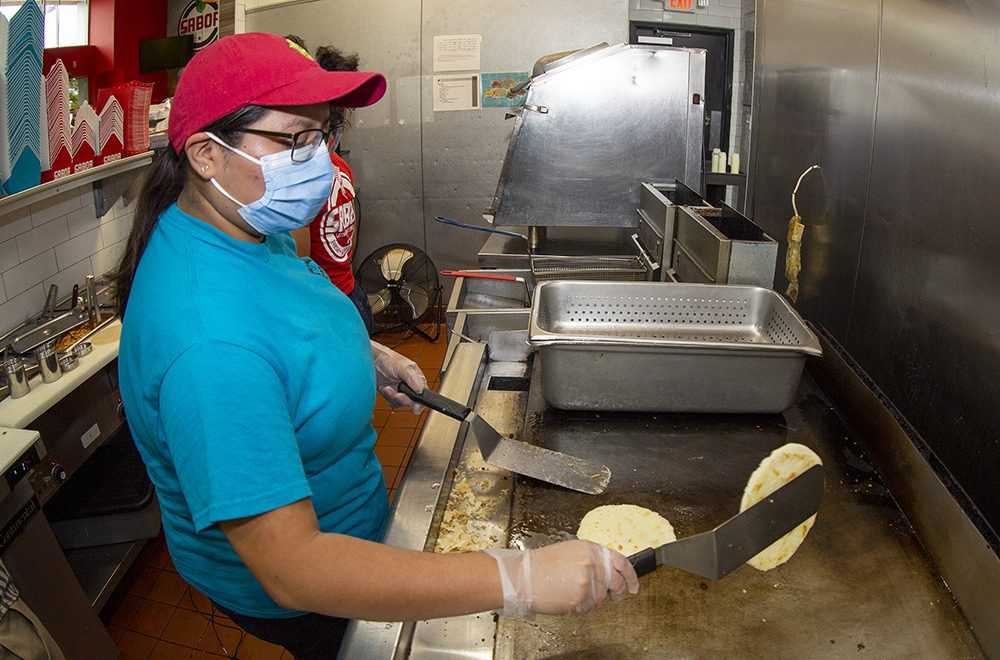 Ada Sanchez, a Sabor Latin Street Grill employee, expertly prepares food in the kitchen, demonstrating the career growth opportunities provided by Sabor.