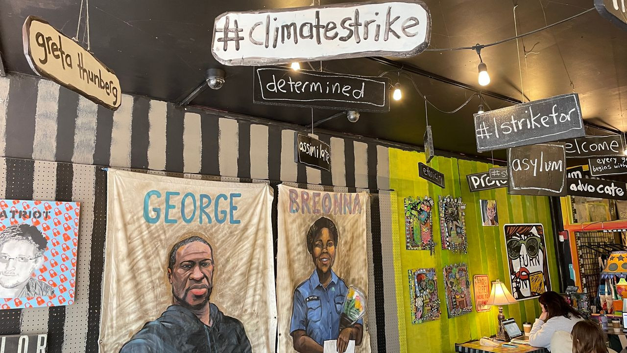 Vibrant interior of Third Street Stuff coffee shop in Lexington, KY, showcasing social justice-themed artwork by owner Pat Gerhard.