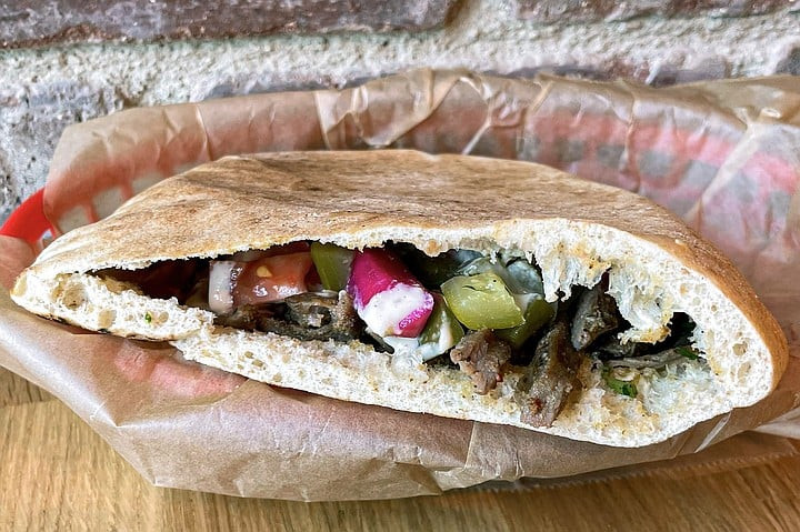 Tahini's O.G. Pita, a flavorful example of authentic Middle Eastern street food, featuring Syrian steak shawarma, fresh vegetables, and creamy tahini sauce.
