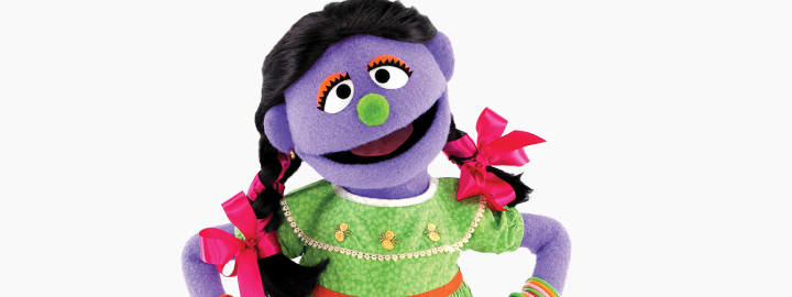 Tuktuki Sesame Street Bangladesh Muppet character reading a book and smiling