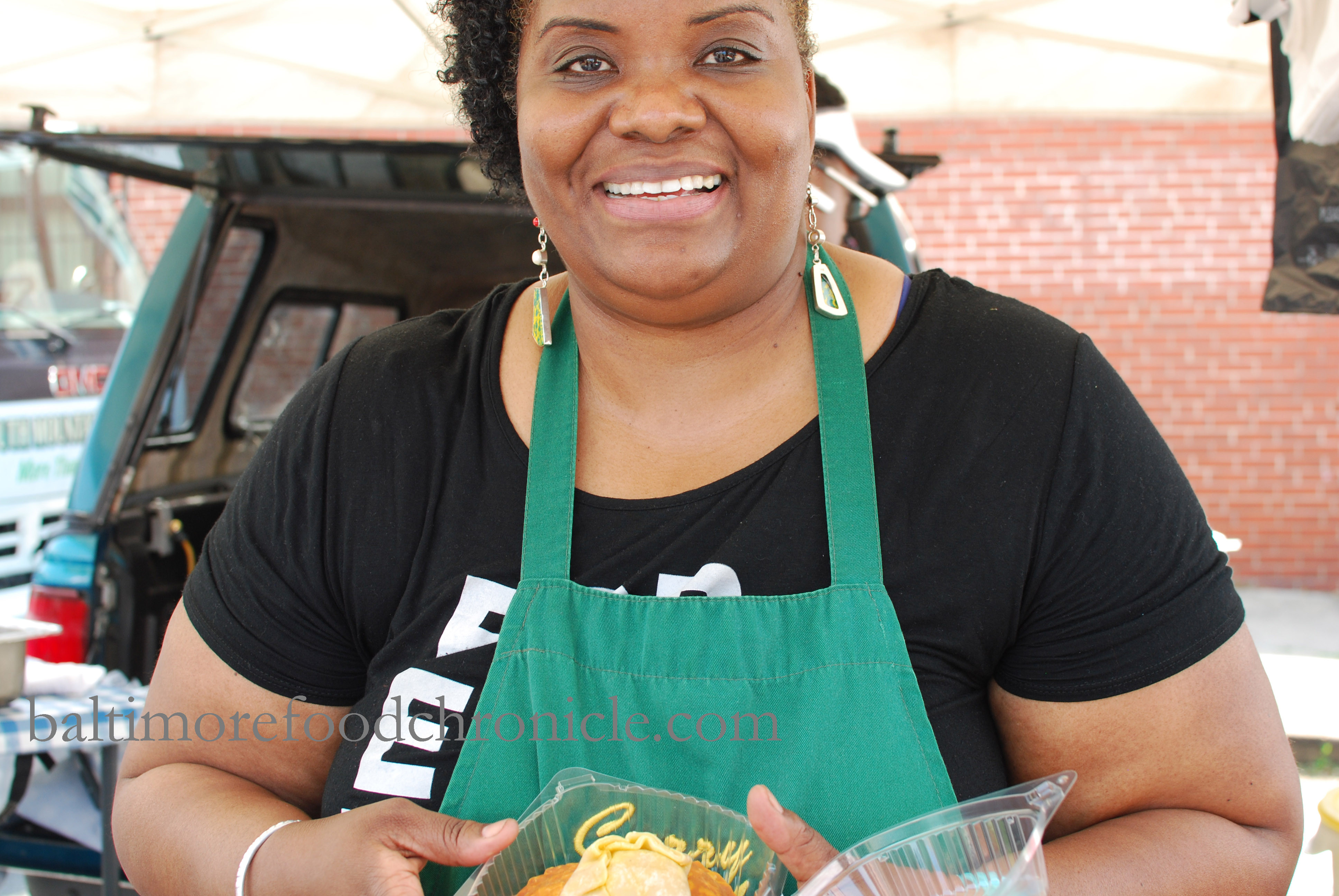 A group of people interacting and laughing at the 32nd Street Farmers Market, emphasizing the social and community-focused atmosphere of the Waverly Market in Baltimore.