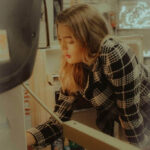 A woman with a thoughtful expression, looking into her refrigerator, surrounded by various food items, contemplating what to eat for dinner.